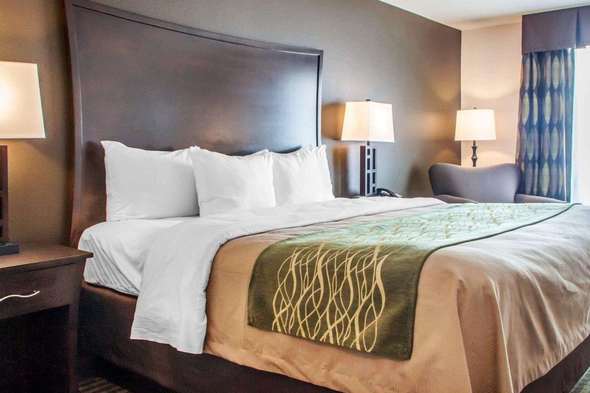 A hotel room with a large bed, two bedside tables, and two lamps.