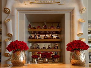 A luxurious interior with a central display of red roses, a mirrored wall, and shelves of liquor bottles.