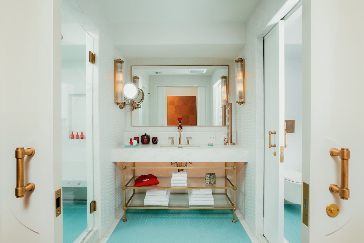 A bathroom with a white vanity, a mirror, and a towel rack.