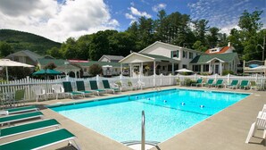 A swimming pool with green lounge chairs and a white picket fence. - Heritage of Lake George (Lake George)