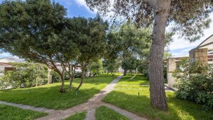 Un sendero bordeado de árboles y césped que conduce a un edificio con pilares de piedra.