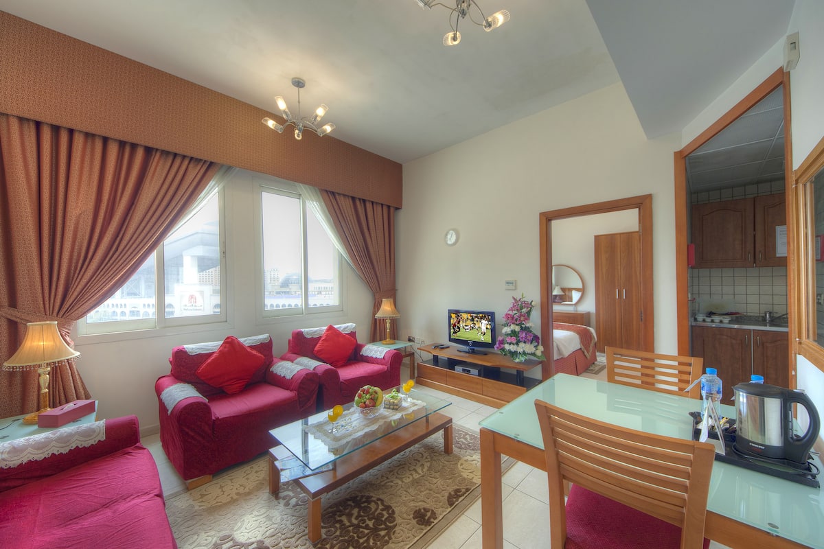A living room with a red sofa, a glass coffee table, and a TV.