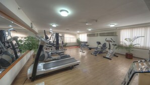 A gym with treadmills, elliptical machines, and stationary bikes, wooden floors, and potted plants. - La villa Najd Hotel Apartments (Dubai)