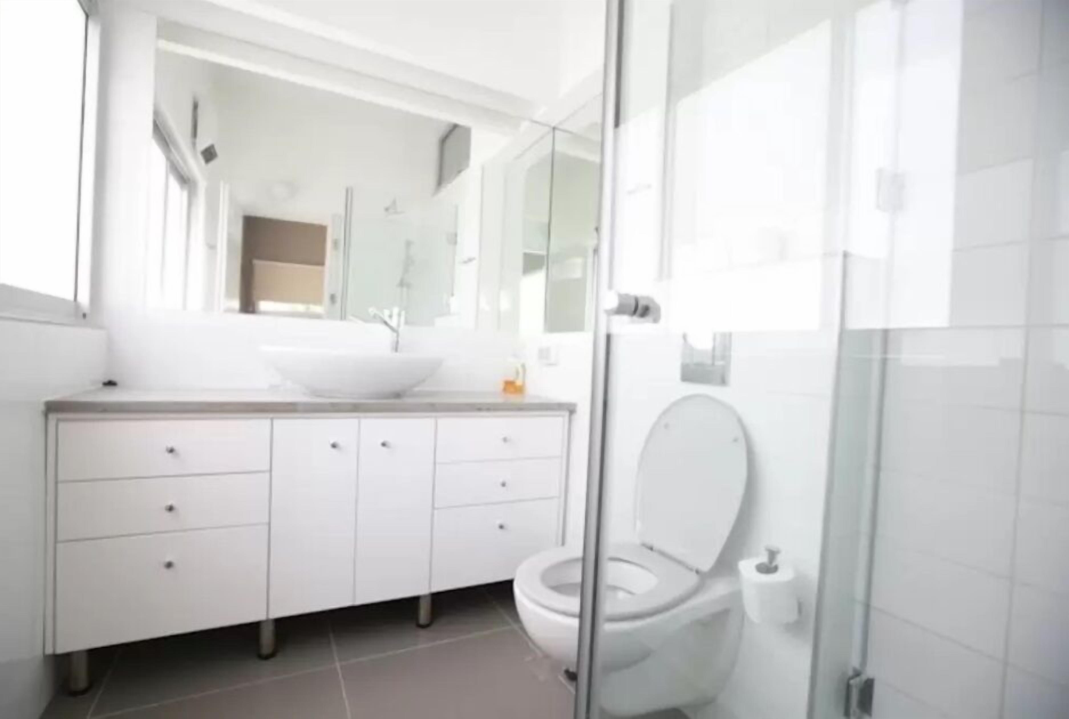 A modern bathroom with a white sink, vanity, and toilet.