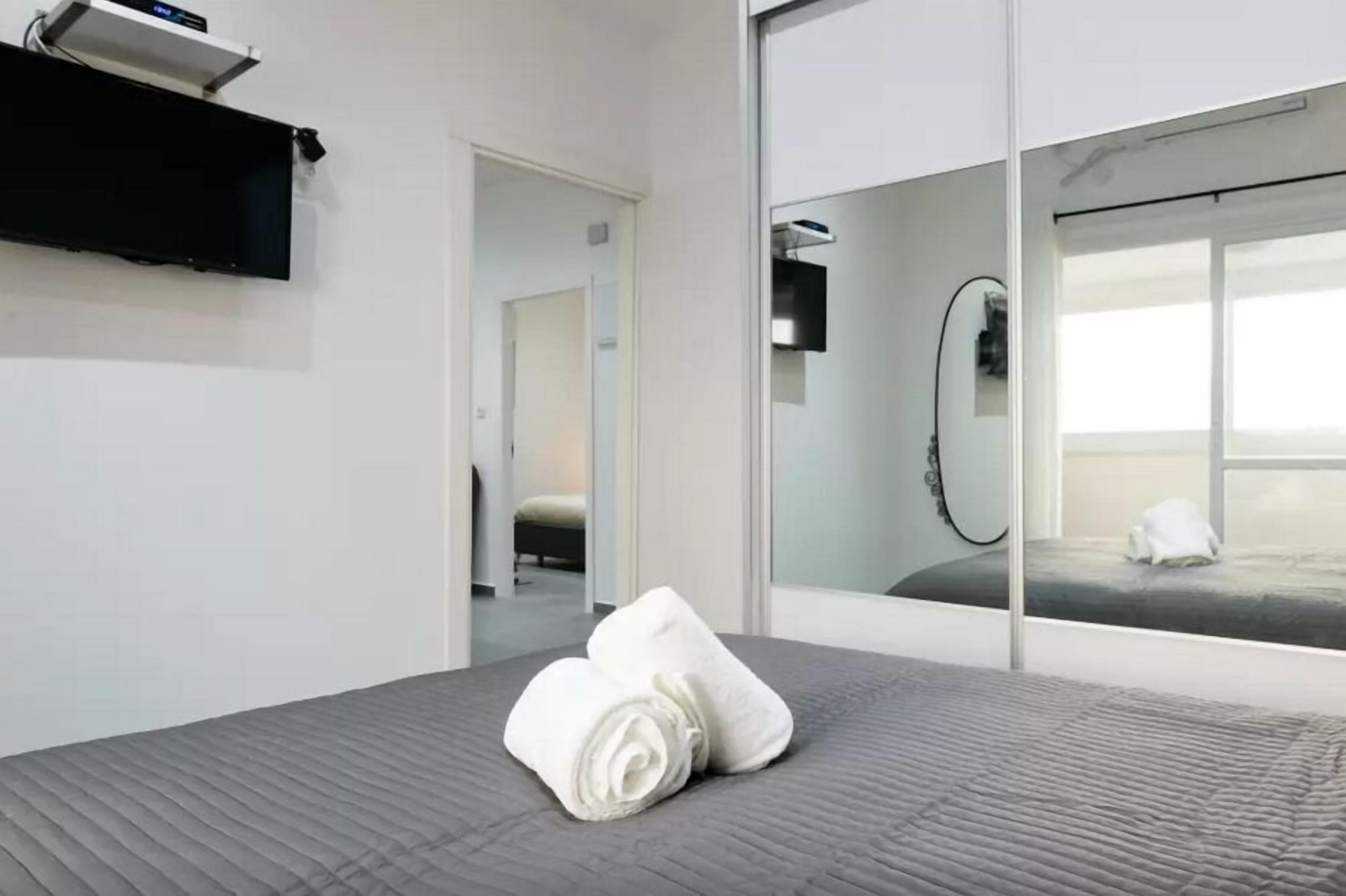 Ein modernes Hotelzimmer mit einem großen Bett, einem Spiegel und Blick aufs Meer.