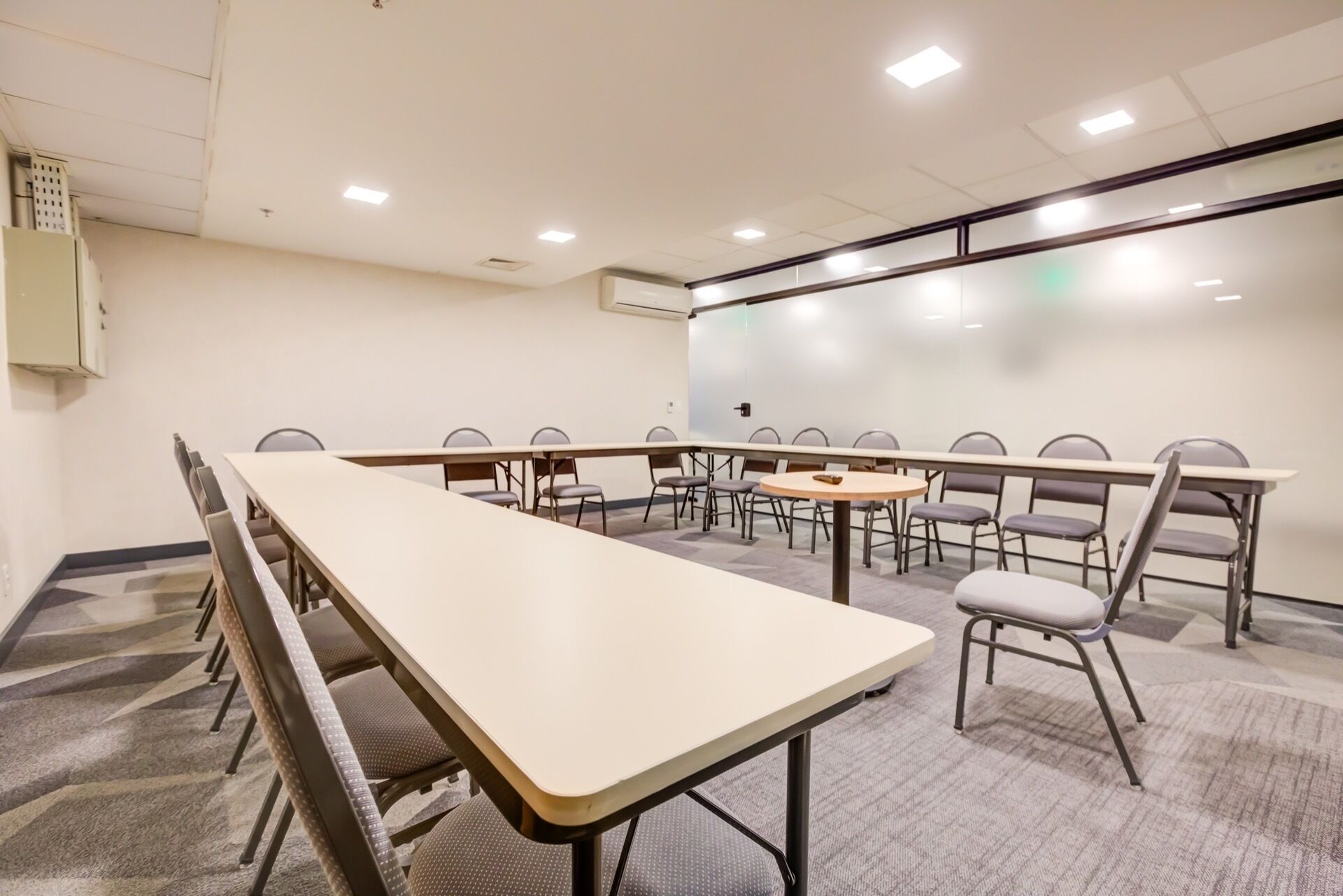 Un salón de conferencias con una larga mesa, varias sillas, una pizarra y una pantalla de proyector.