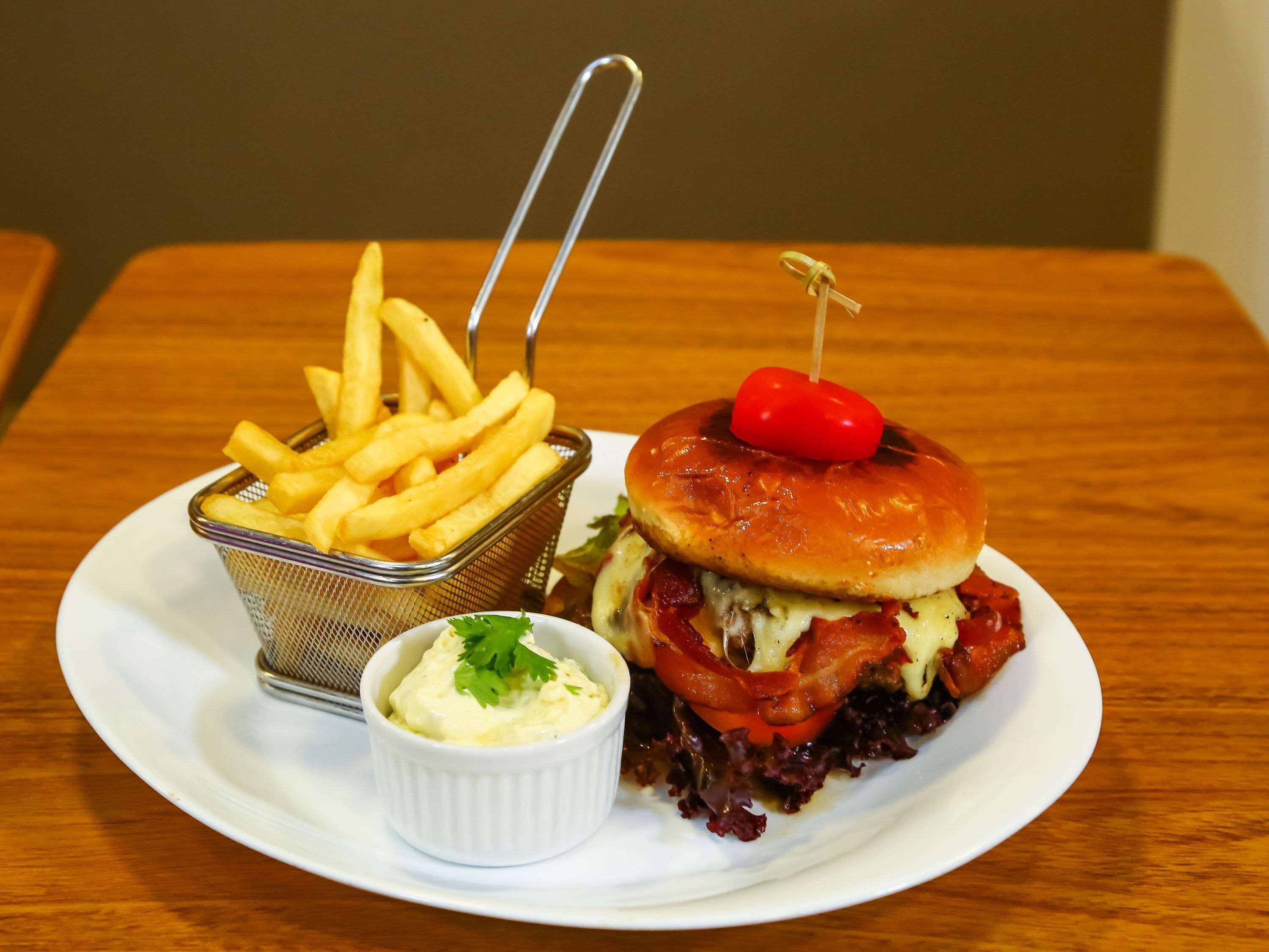 Ein Teller mit einem Hamburger, Pommes und einer kleinen Soße.