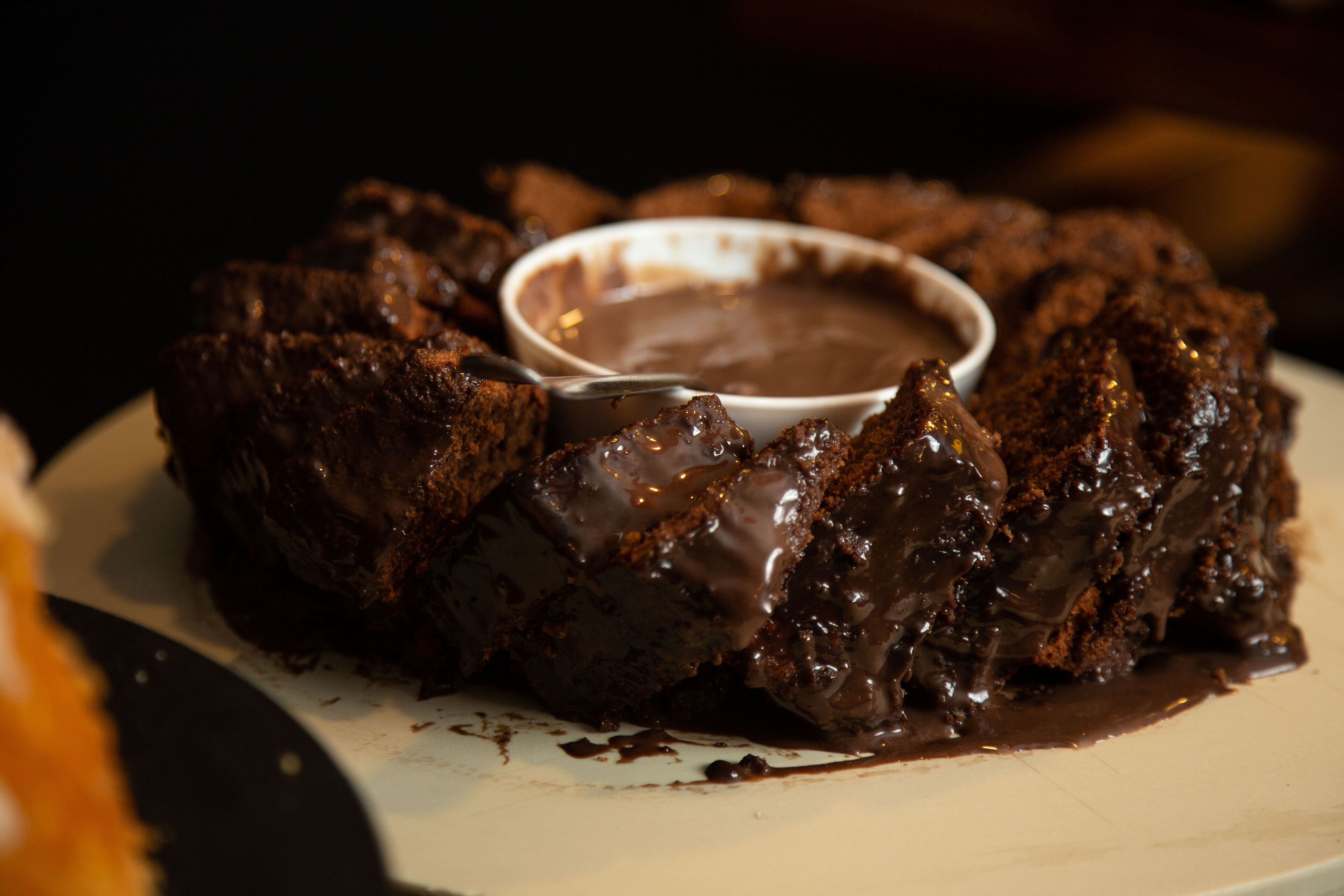 A chocolate dessert with a dipping sauce on a plate.