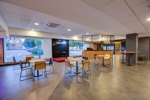 A modern cafe with a stage for live music, a bar area, and a seating arrangement with tables and chairs. - ibis Rio de Janeiro Shopping Nova America (Rio de Janeiro)