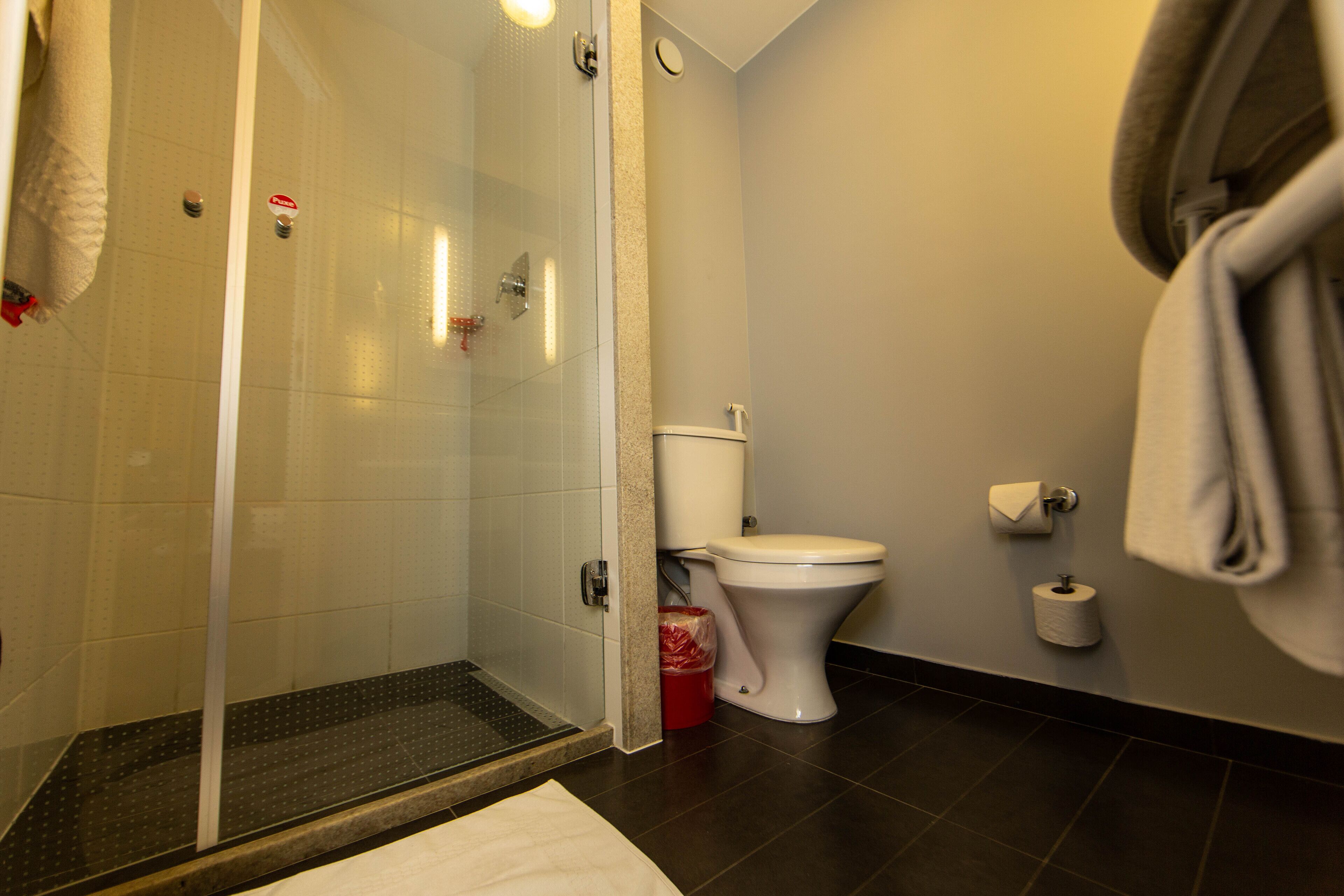 A bathroom with a glass-enclosed shower, a toilet, and a towel hanging on the wall.
