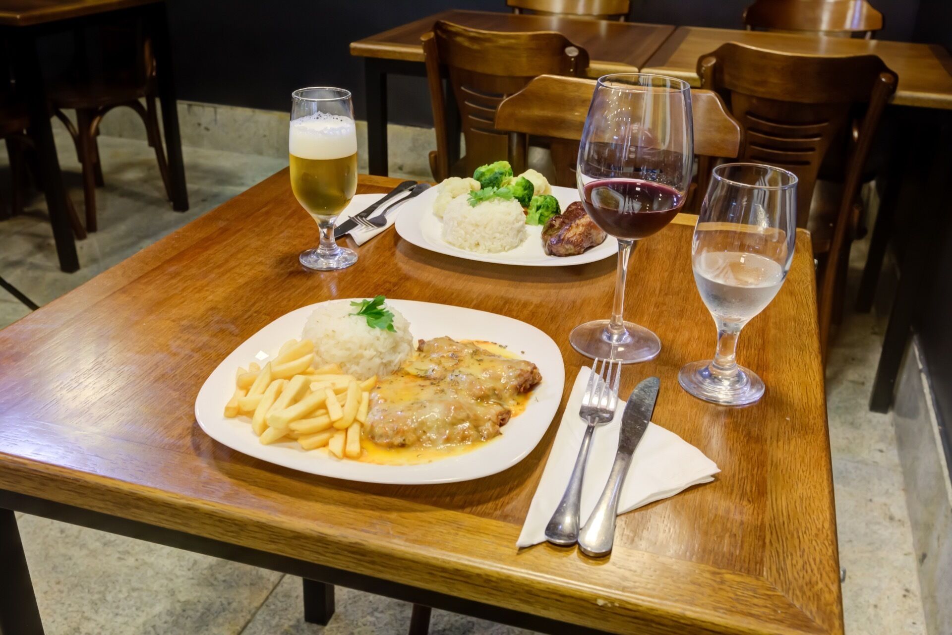 A dining table with plates of food and glasses of wine.