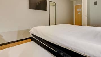 Habitación de hotel con cama, televisor de pantalla plana en la pared, una puerta y equipo de aire acondicionado.