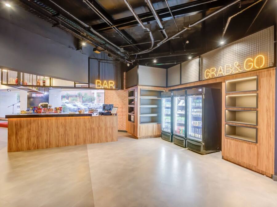 A modern bar area with a wooden counter and neon signage.