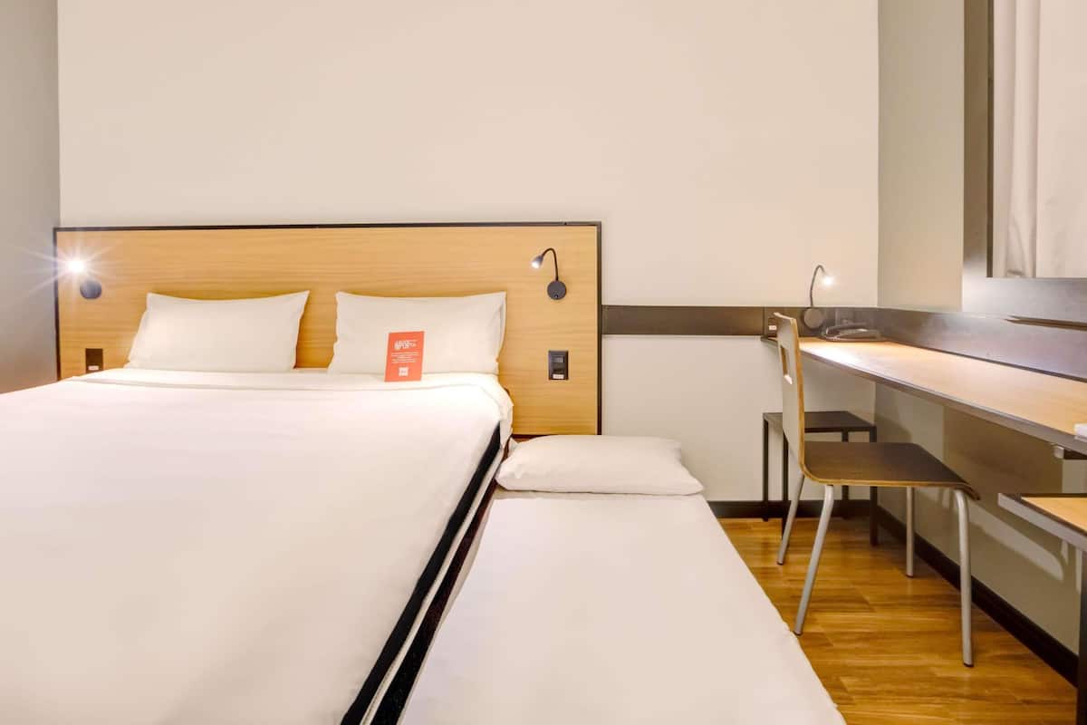 Ein Hotelzimmer mit einem hölzernen Kopfteil, einem Schreibtisch und einem Stuhl.