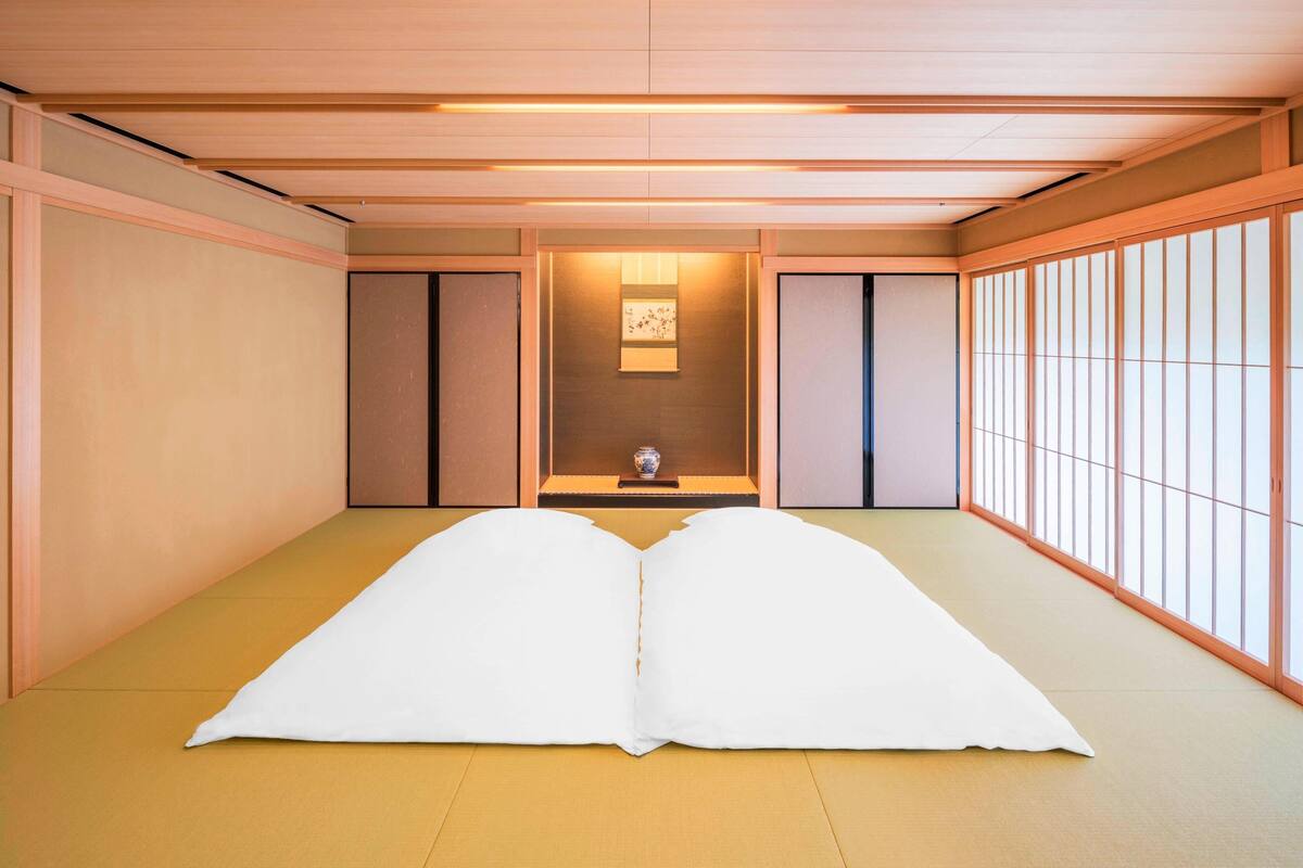 A traditional Japanese room with tatami flooring, sliding doors, and a small table with a vase.