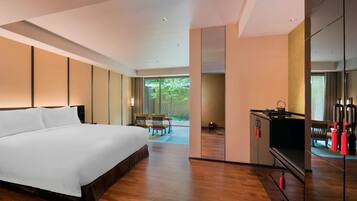 A modern hotel room with a large bed, a dining area, and a kitchen.