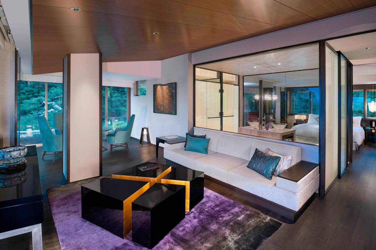 A modern living room with a white sofa, black coffee table, and a glass partition.