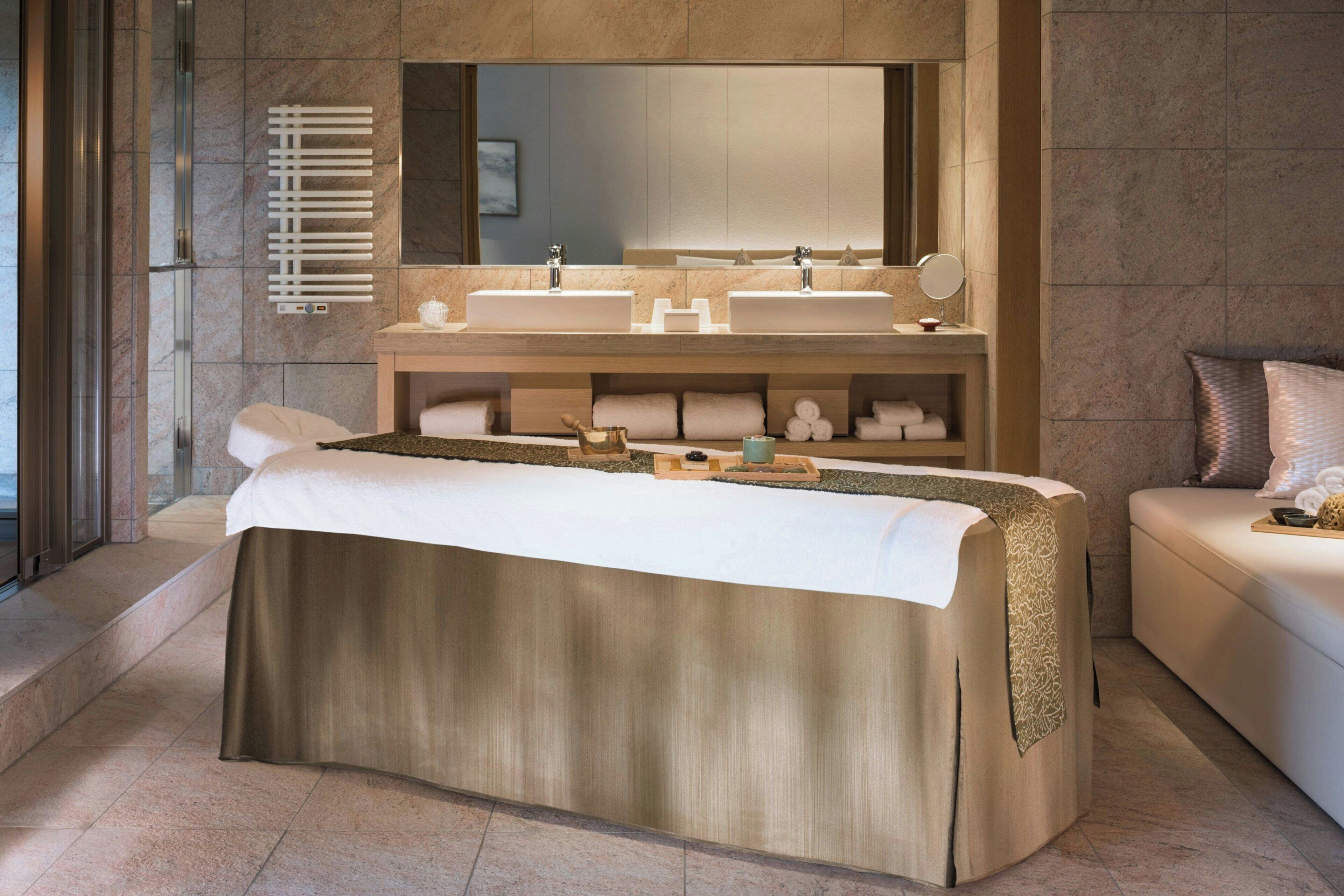 Un baño moderno con una bañera grande, dos lavamanos, un tocador y un espejo amplio.