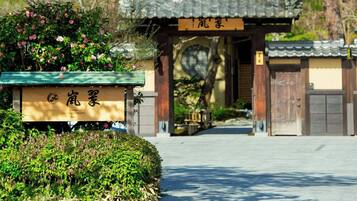 A traditional Japanese gate with a sign, surrounded by lush greenery and cherry blossoms.