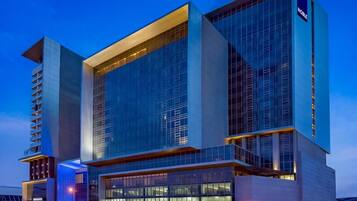 A modern hotel with a prominent glass facade, multiple floors, and a visible 'Noble' sign.