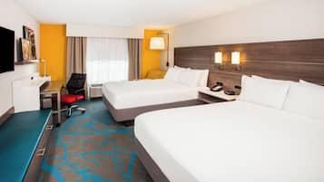 A hotel room with two beds, a desk, a chair, a TV, and a window with curtains.