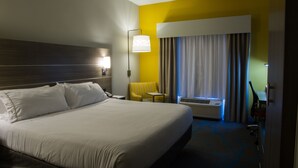 A hotel room with a large bed, a bedside table, a lamp, a chair, an air conditioning unit, and a window with curtains. - Holiday Inn Express & Suites Litchfield West by IHG (Litchfield)