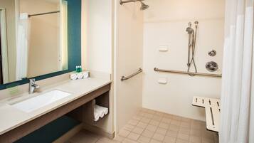 A modern bathroom with a sink, mirror, and shower area.