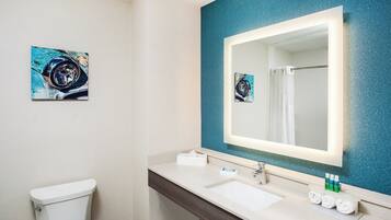 A bathroom with a white toilet, a sink with a mirror, and a blue textured wall.