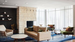 Una sala de estar moderna con un sofá color crema, dos sillones, una mesa de centro y un televisor frente a una pared de piedra.