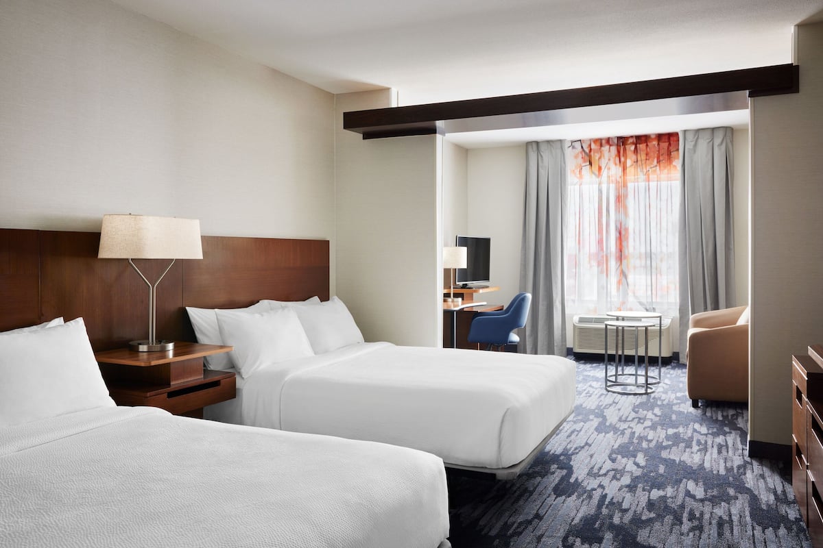 Une chambre d’hôtel avec deux lits, un bureau, une chaise et un téléviseur.