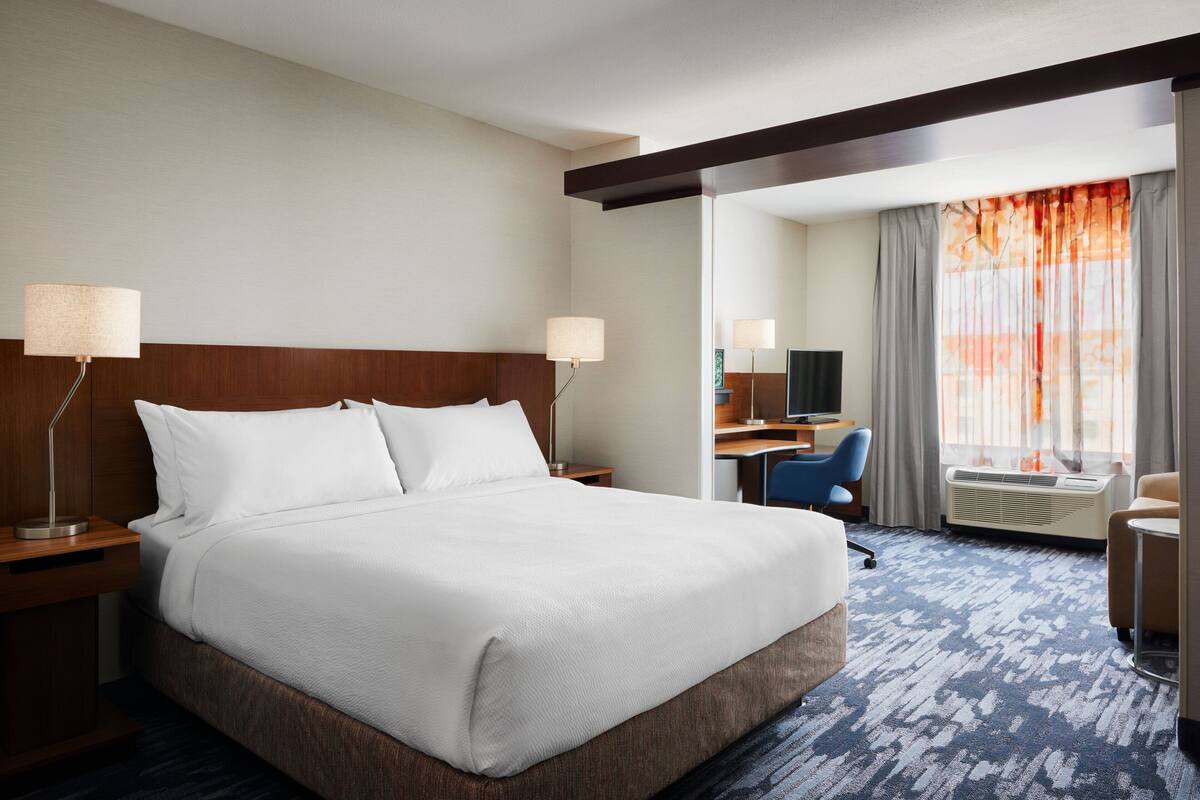 Une chambre d’hôtel avec un grand lit, un bureau, une chaise et un téléviseur.