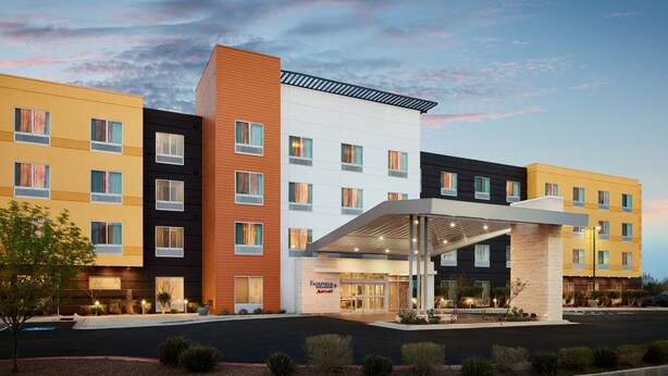 Un hotel de varios pisos con fachada moderna, que presenta una combinación de colores amarillo, negro y blanco. La entrada tiene un vestíbulo cubierto y se puede ver el letrero de Fairfield Marriott.