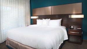 Una habitación de hotel con una cama grande, una mesita de noche con teléfono e iluminación integrada en la cabecera.