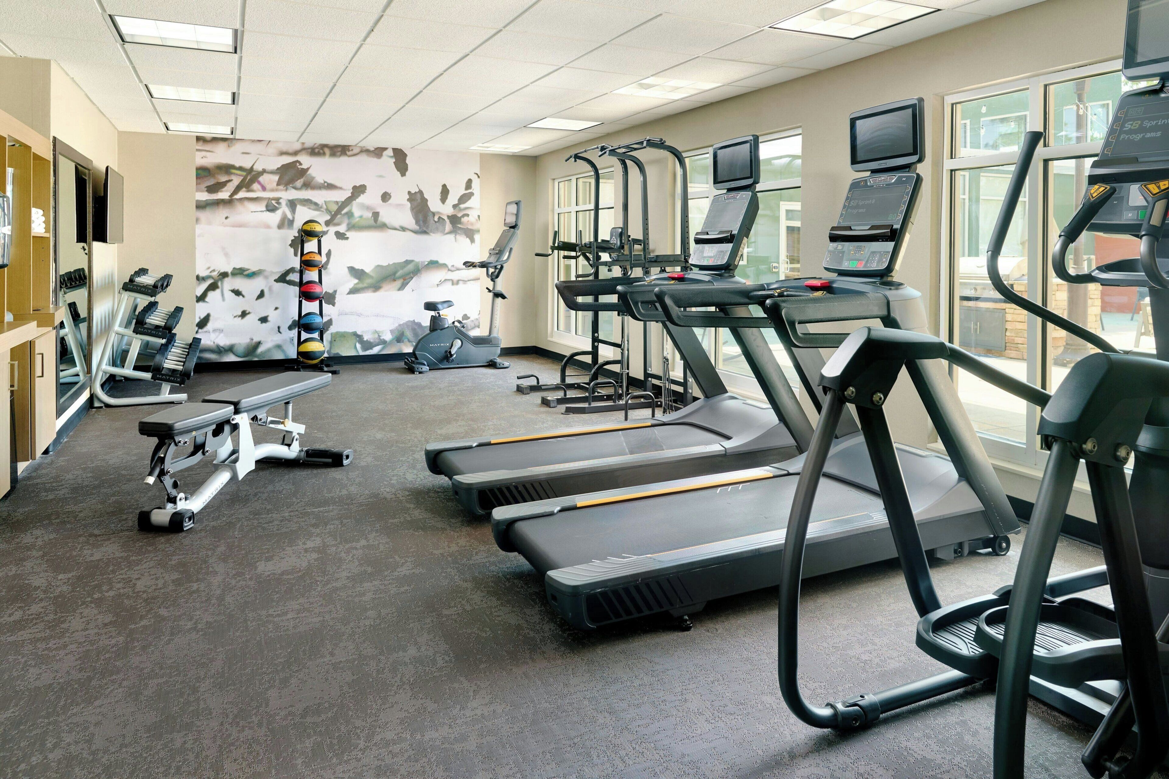 Une salle de sport équipée de tapis de course, d’un vélo d’appartement et d’un banc de musculation.