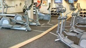 A gym with multiple treadmills, a wall-mounted TV, and a shoe rack. - Residence Inn Augusta (Augusta)