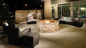An outdoor seating area with wicker furniture and a stone fire pit. - Residence Inn Augusta (Augusta)