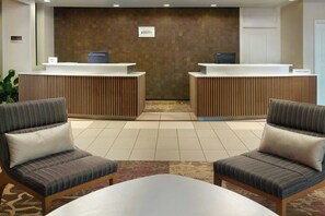 A reception area with two reception desks, a carpeted floor, and two upholstered chairs. - Residence Inn Augusta (Augusta)