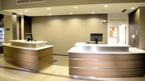 A reception area with two counters, a tiled wall, and a door in the background. - Residence Inn Augusta (Augusta)