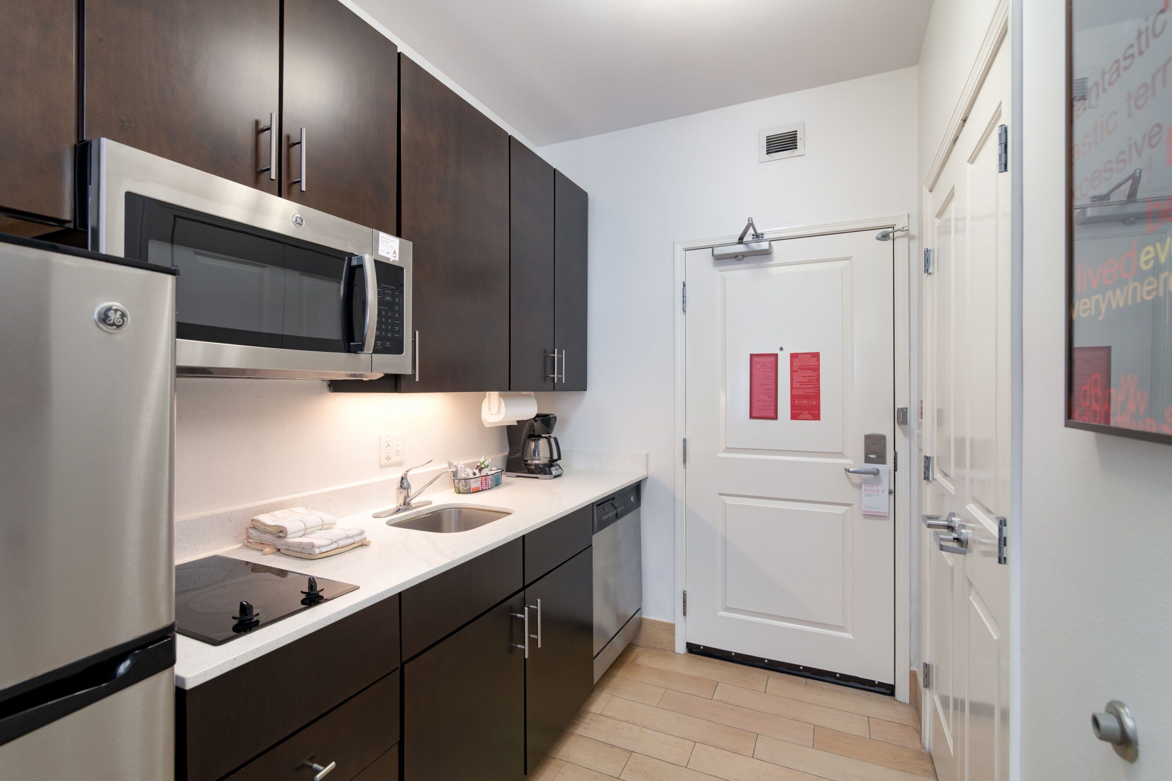 A modern kitchen with dark cabinets, stainless steel appliances, and a white countertop.