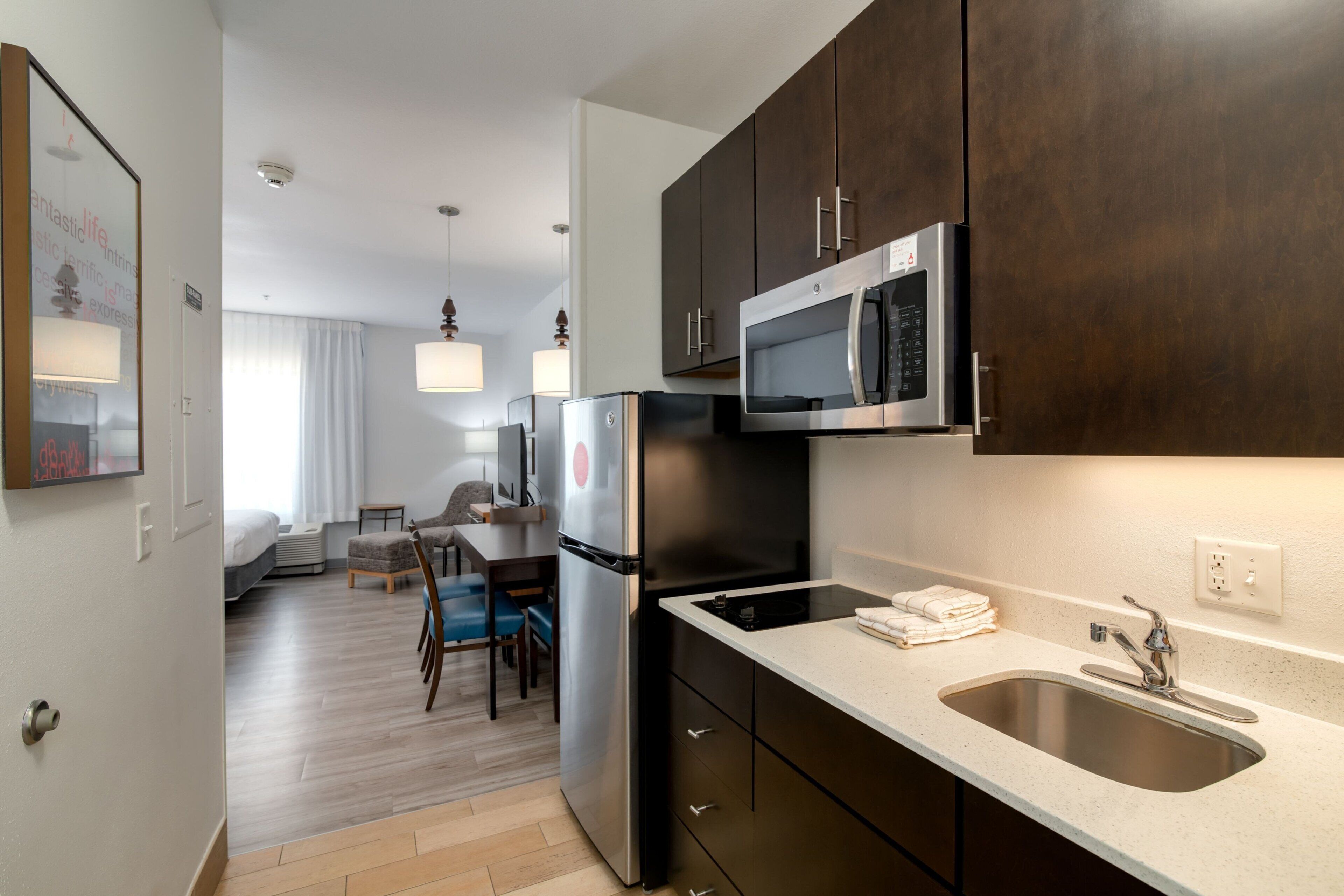 A modern kitchen with dark cabinets, stainless steel appliances, and a white countertop.