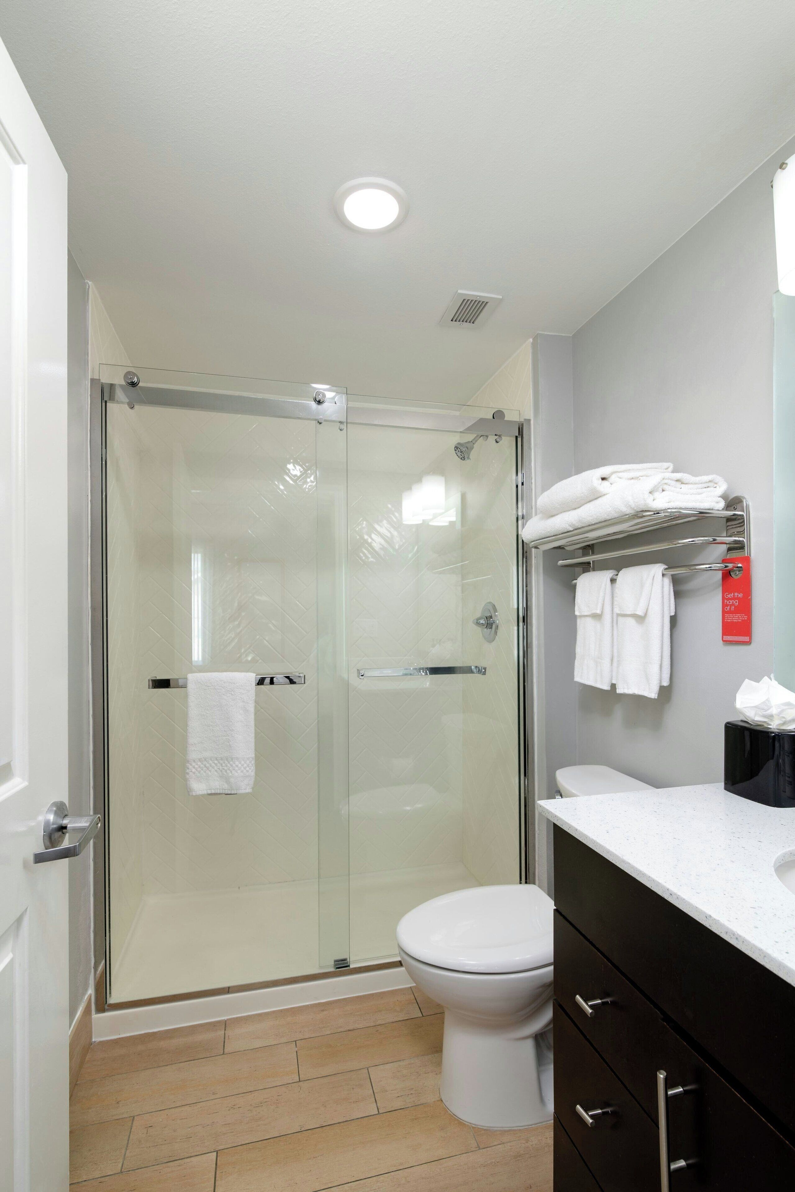 A modern bathroom with a glass-enclosed shower, a white toilet, and a vanity with a countertop.
