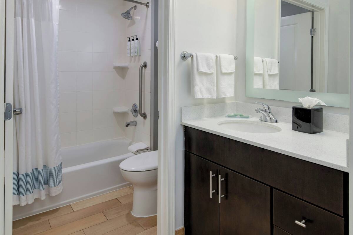 A bathroom with a bathtub, toilet, and vanity with a mirror and sink.