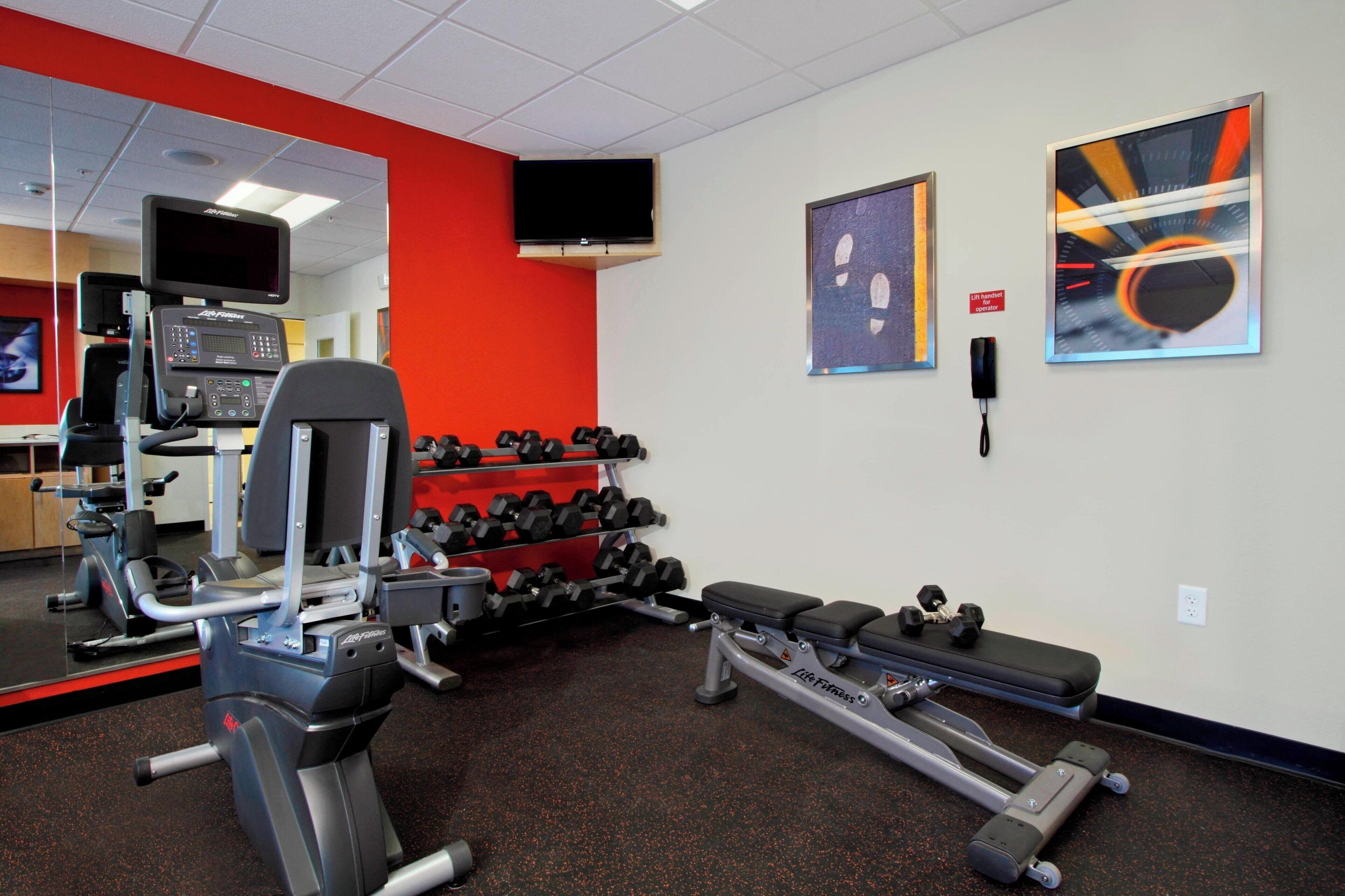 A gym with cardio equipment, dumbbells, and benches.