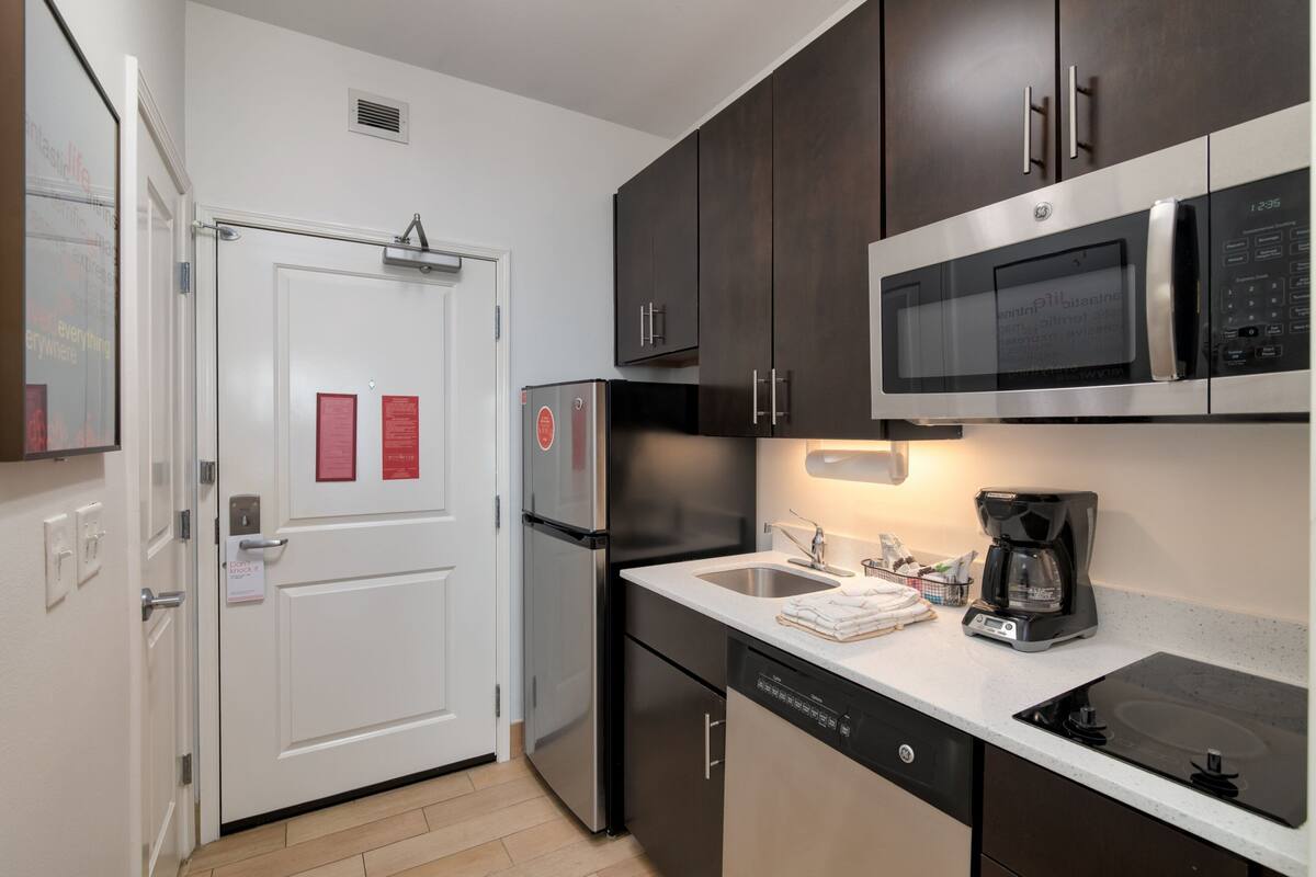 A modern kitchen with stainless steel appliances, a dishwasher, and a coffee maker on the counter.