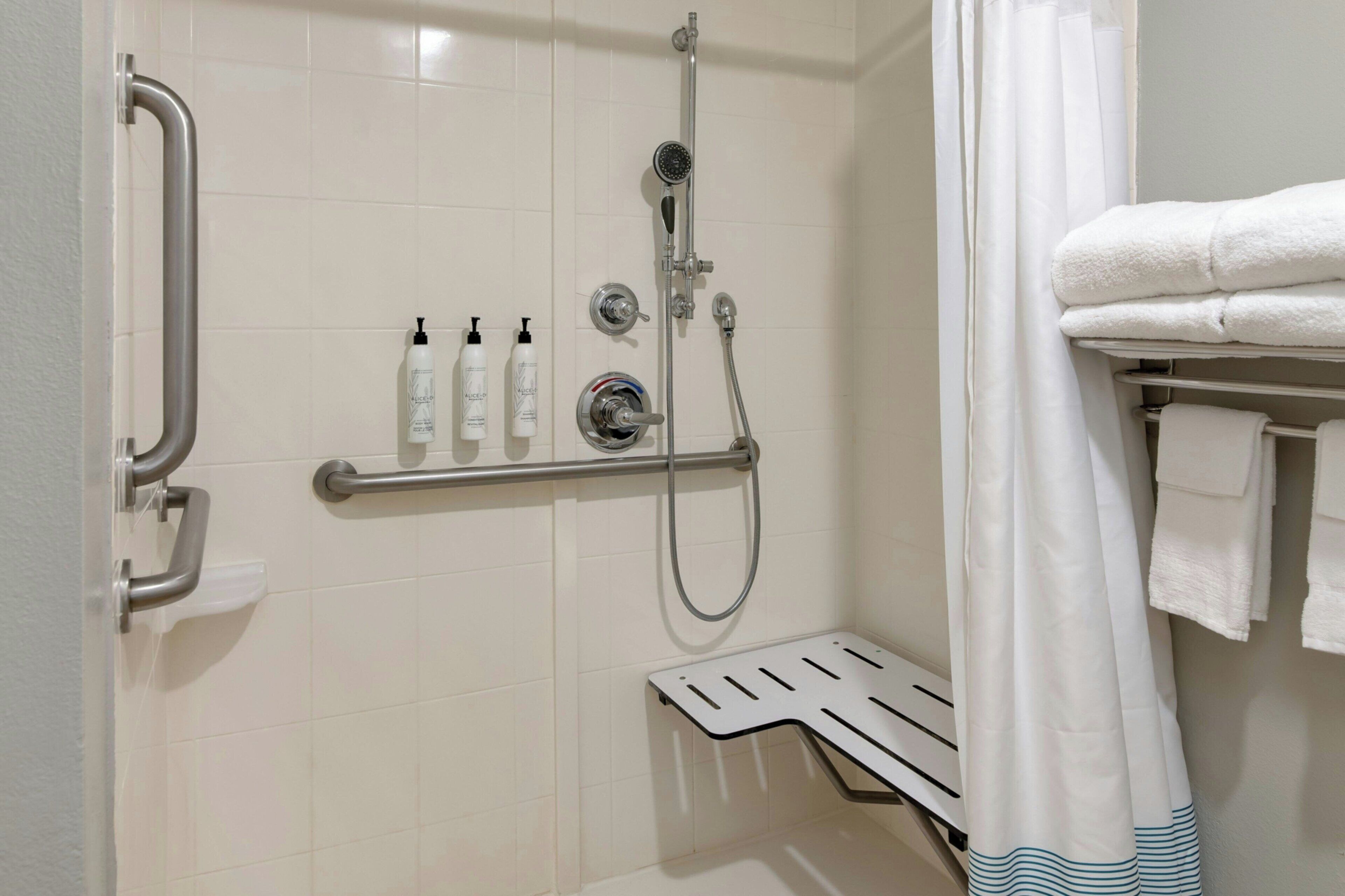 A shower area with a grab bar, a towel rack, and a showerhead.