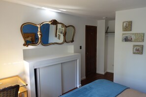 A bedroom with a bed, a desk, a mirror, and a wardrobe. - Le Petit Palais (Buenos Aires)