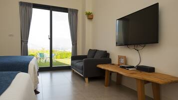 Una habitación de hotel con cama, sofá, televisión montada en la pared y una mesa.
