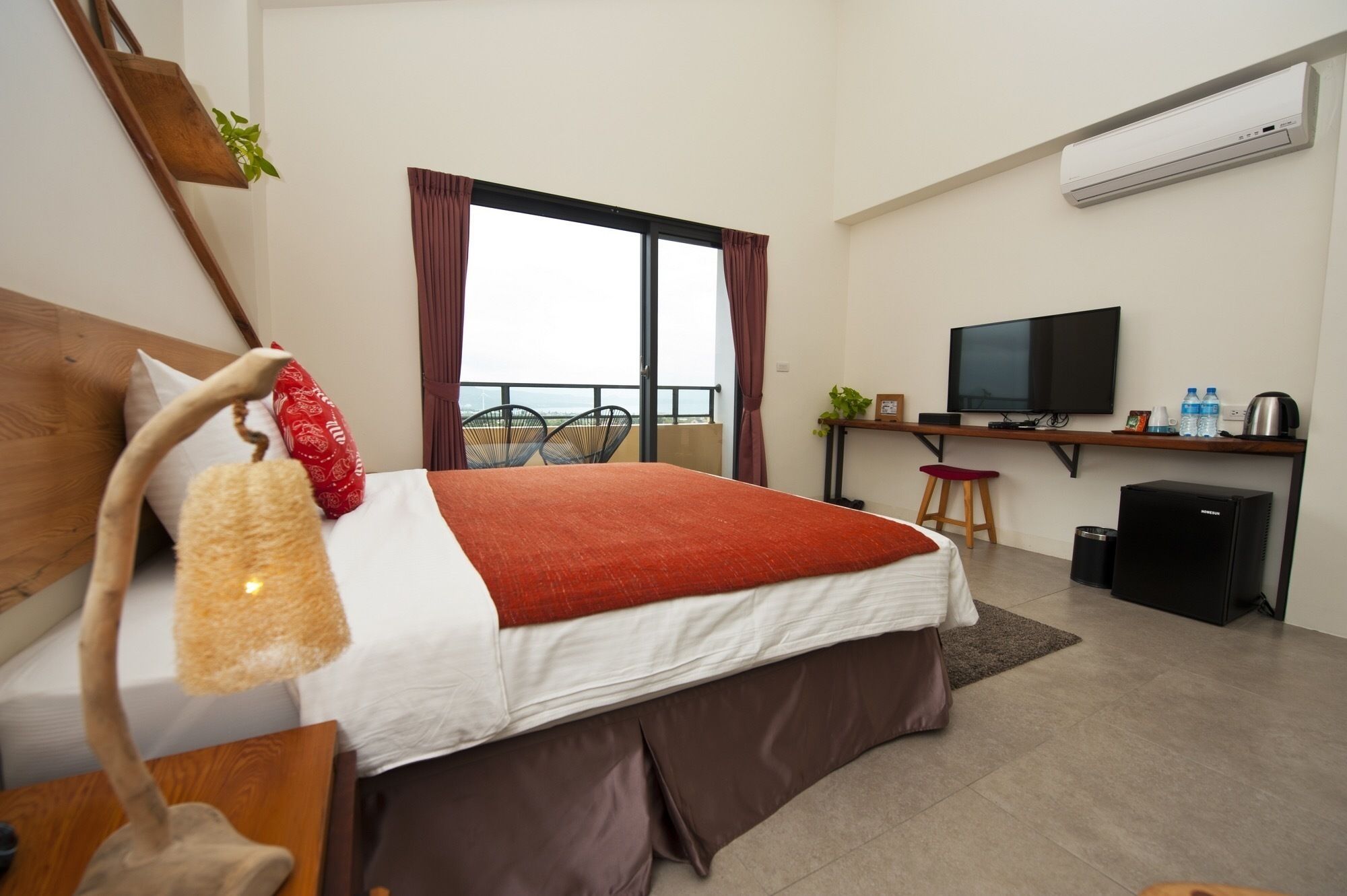 Une chambre d’hôtel comprenant un lit, un bureau avec une télévision, une petite kitchenette et un balcon avec vue.