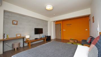 A modern hotel room with a large bed, a flat-screen TV mounted on the wall, a wooden bench, a small stool, and an orange door.