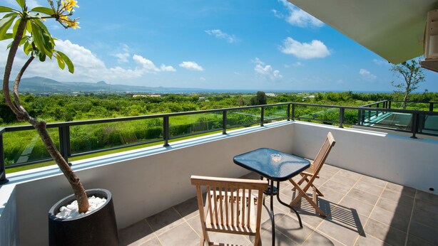 Un balcon offrant une vue sur un paysage verdoyant et des montagnes lointaines.
